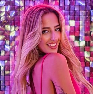 Eine Frau in einem rosa Kleid lächelt vor einer lila Wand .