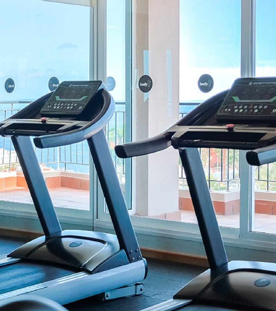 a woman in a white tank top stands in front of palm trees
