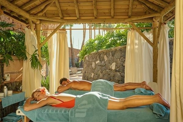 ein Mann und eine Frau sitzen unter Sonnenschirmen am Pool
