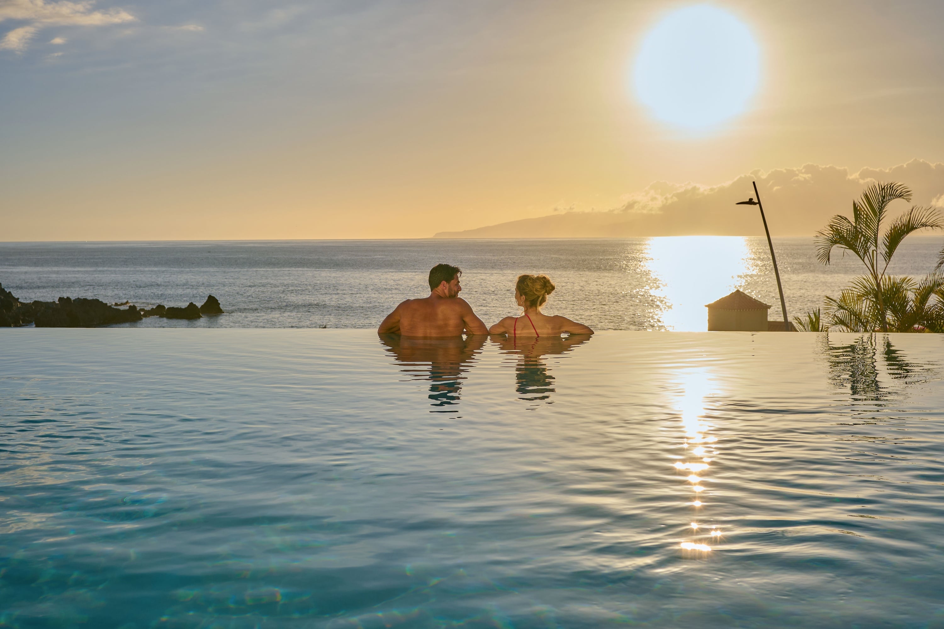 Amantes en batas de spa relajándose en balcón con vistas al mar de Landmar.