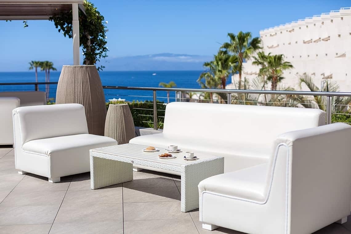 a patio with white furniture and a table with coffee cups on it