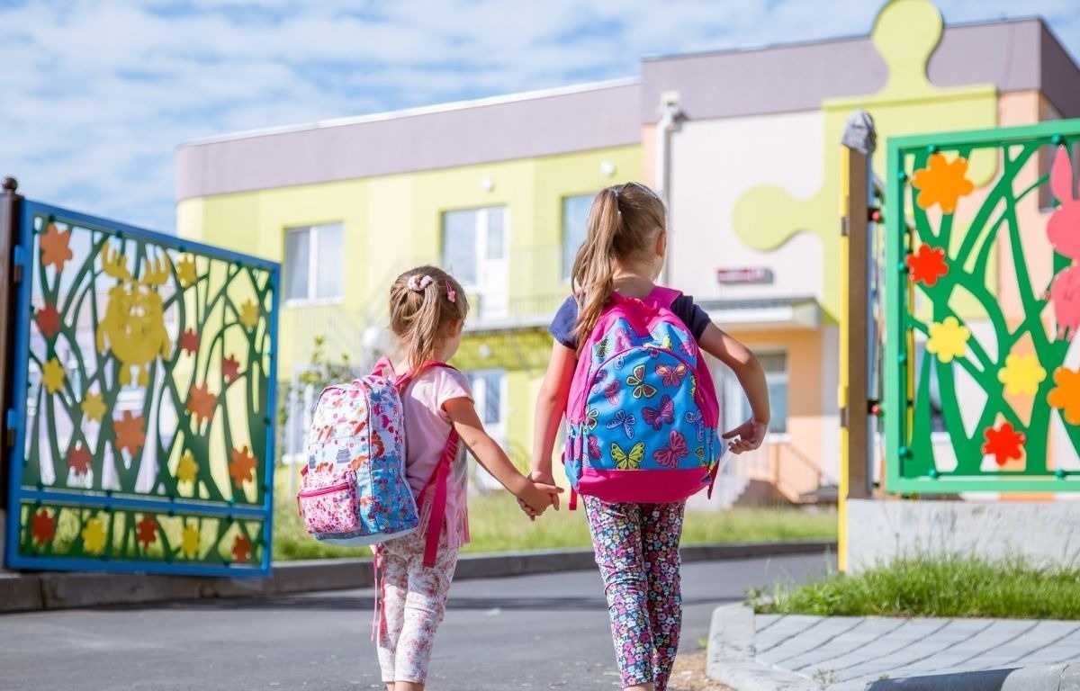 dos niñas con mochilas van a la escuela