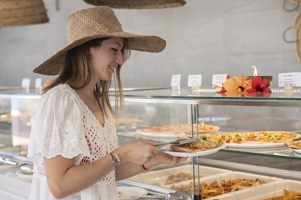 une femme en chapeau de paille mange une pizza dans un restaurant