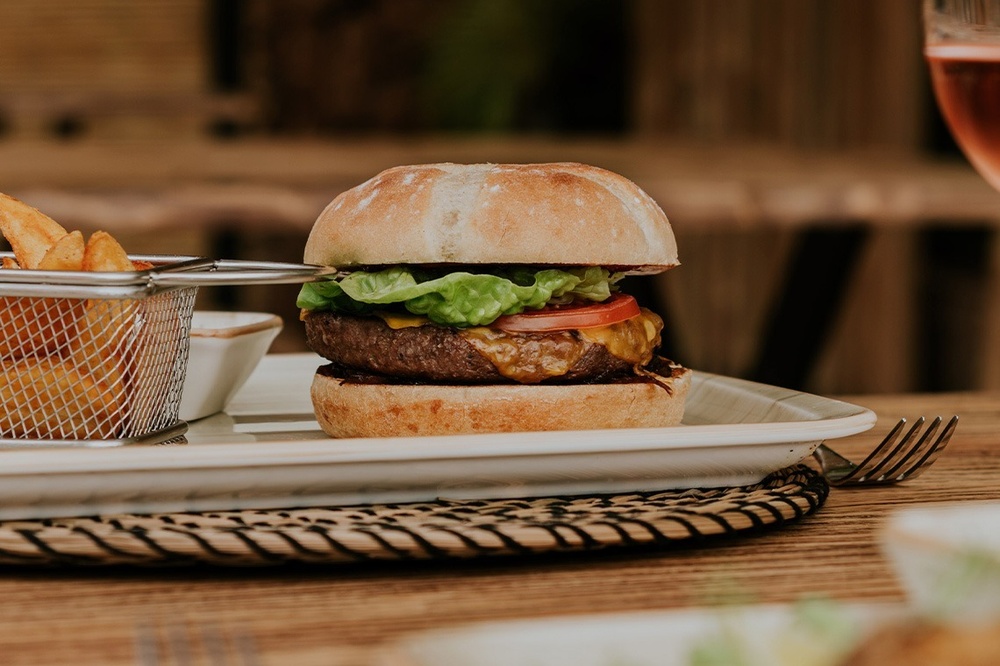 ein hamburger steht auf einem teller neben einem korb mit pommes frites