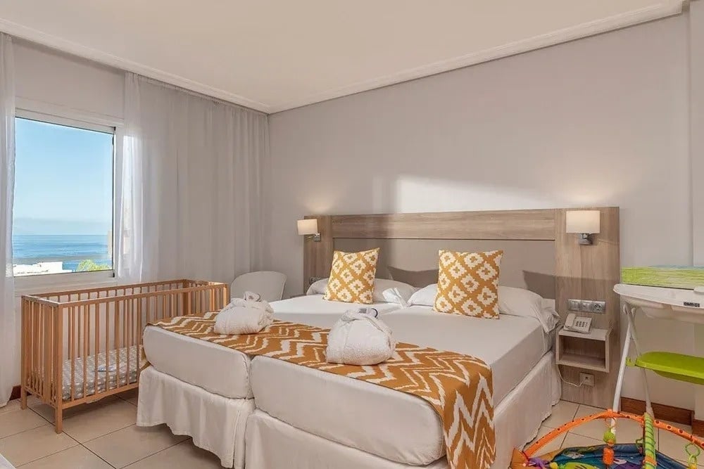 une chambre d' hôtel avec un lit double et un berceau