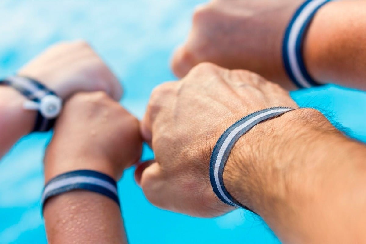 tres personas con pulseras azules y blancas en sus muñecas