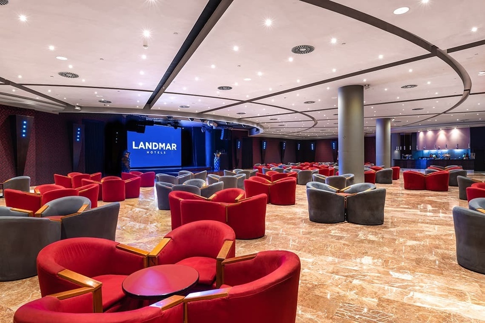 une grande salle avec des chaises rouges et un grand écran qui dit landmar hotels