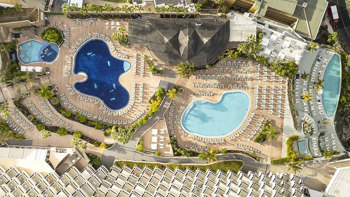 Landmar resort with pools, loungers, and palm trees, aerial view.