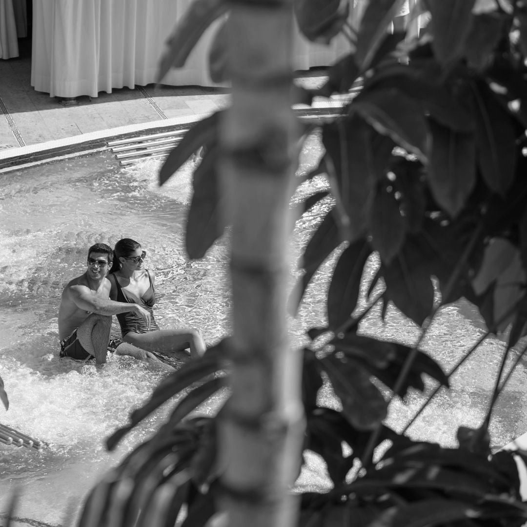 a woman wearing a hat and sunglasses is laying in a pool