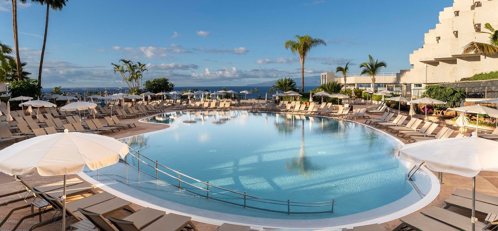 a large swimming pool surrounded by chairs and umbrellas