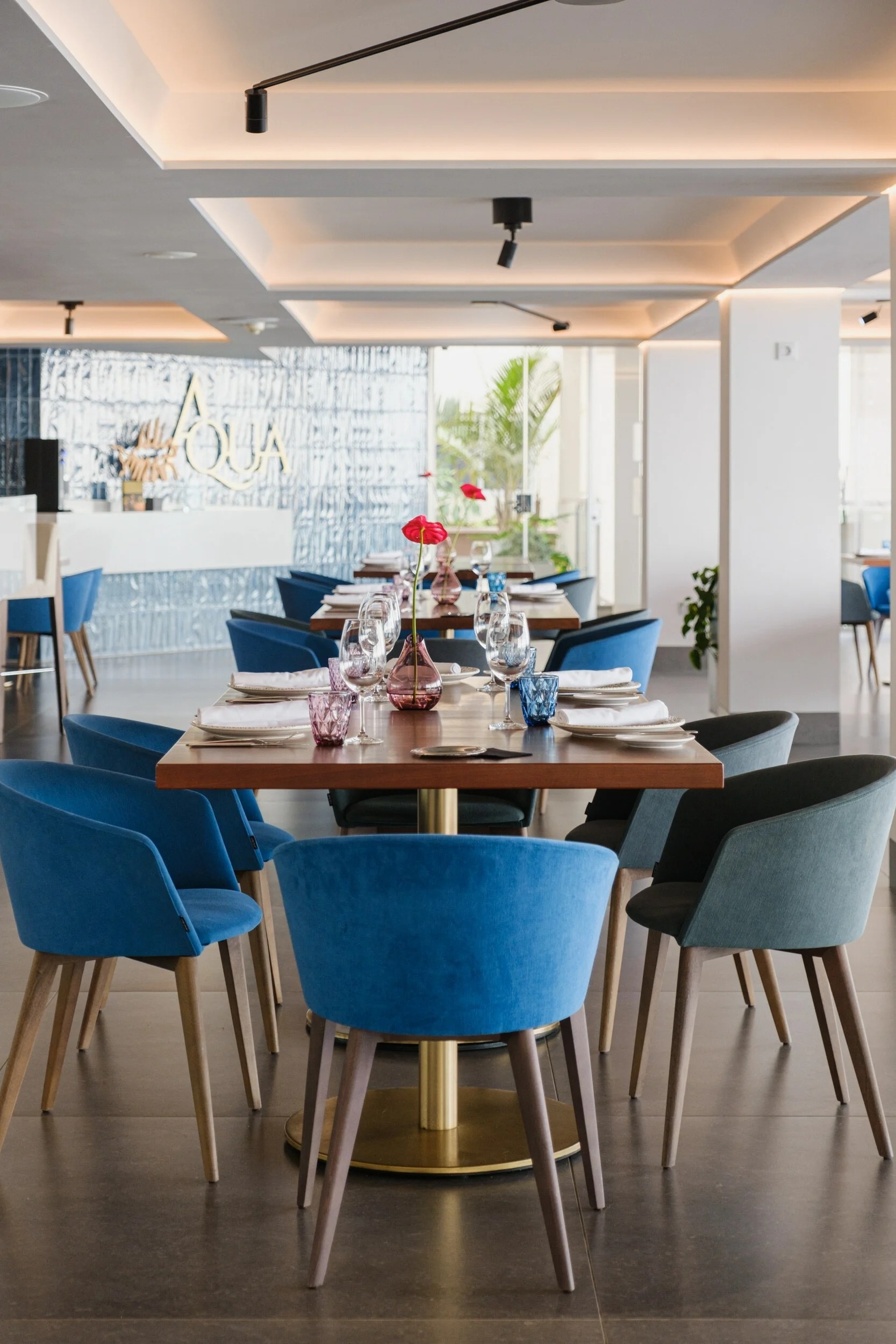 un restaurante con mesas y sillas azules y la palabra aqua en la pared