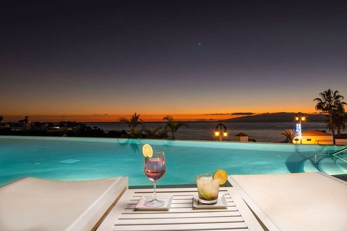 una piscina infinita con una copa de vino y un cóctel