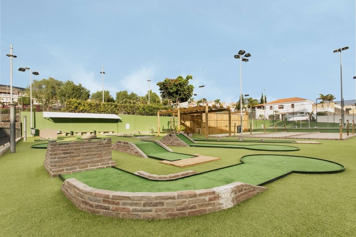 un campo de minigolf con un edificio de ladrillos al fondo