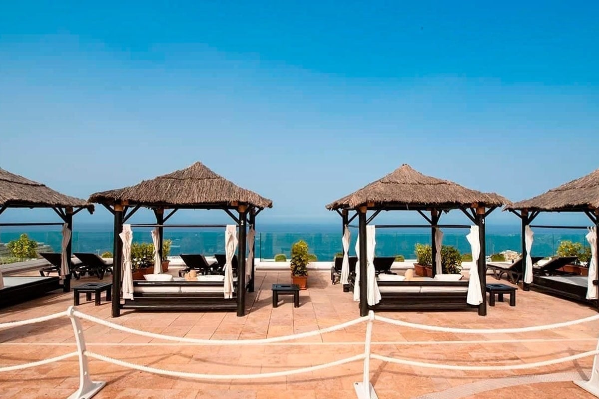 una fila de gazebos con sillas y mesas frente al océano