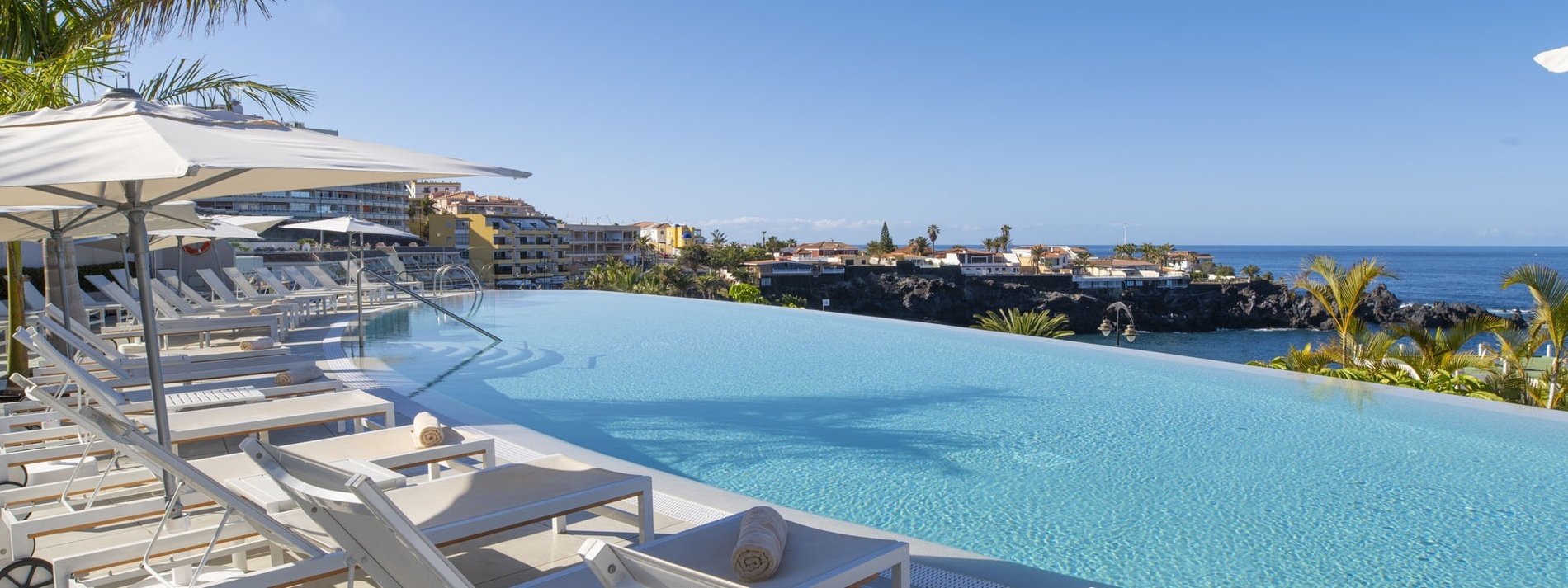 une piscine avec des chaises et des parasols à côté de l' océan