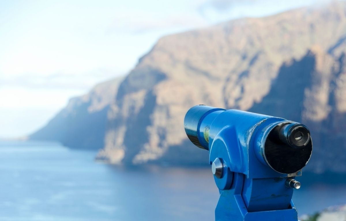 a blue telescope looks out over a body of water