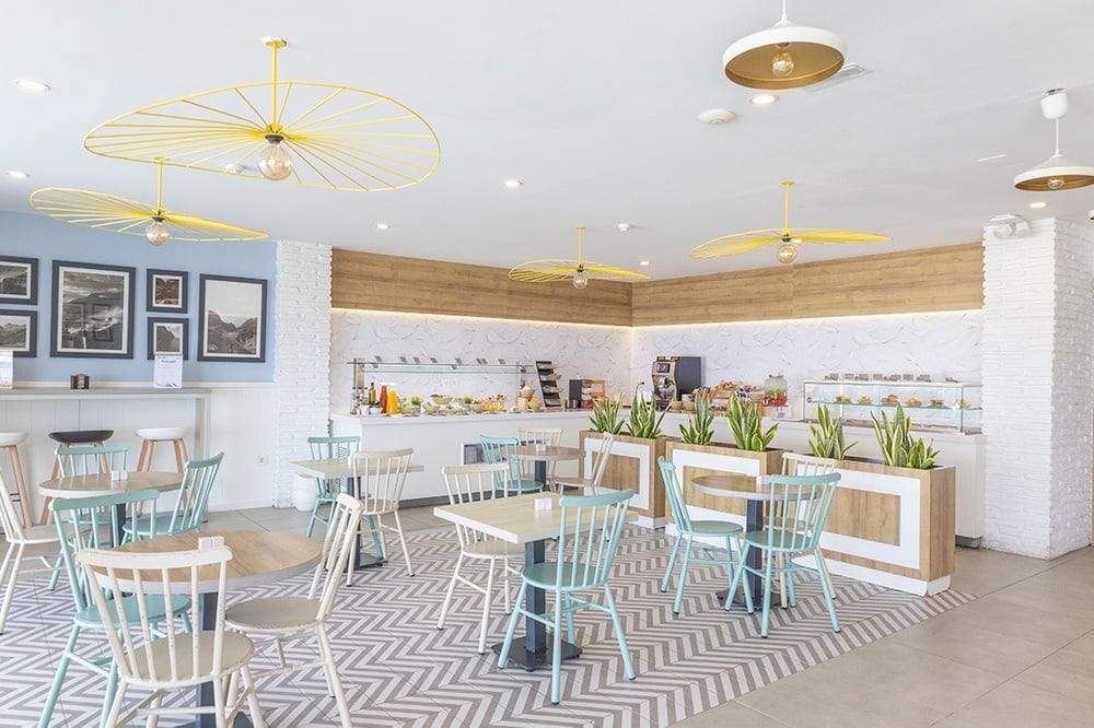 une salle à manger avec des chaises bleues et des tables blanches