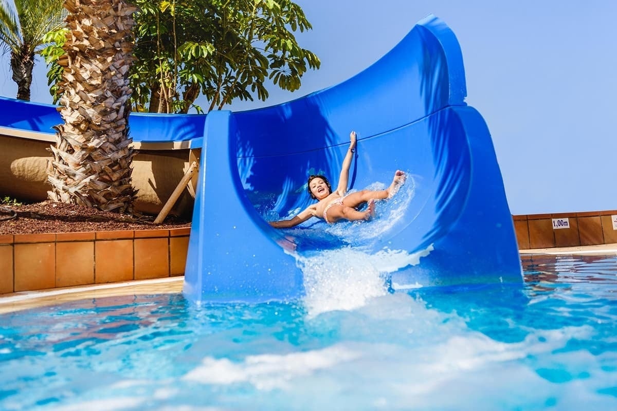 a child is going down a blue water slide in a pool