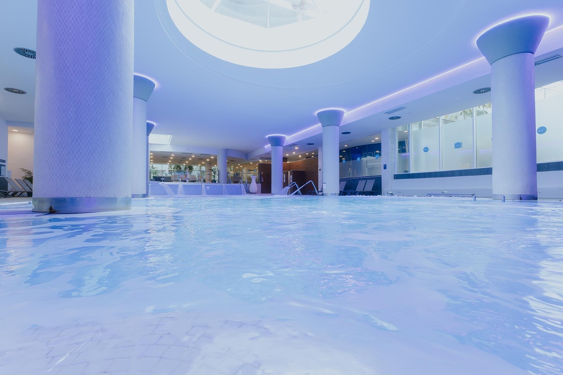 a large indoor swimming pool is lit up with purple lights