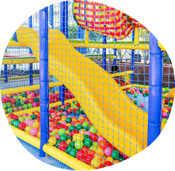 un área de juegos colorida con un tobogán rosa y un paraguas amarillo