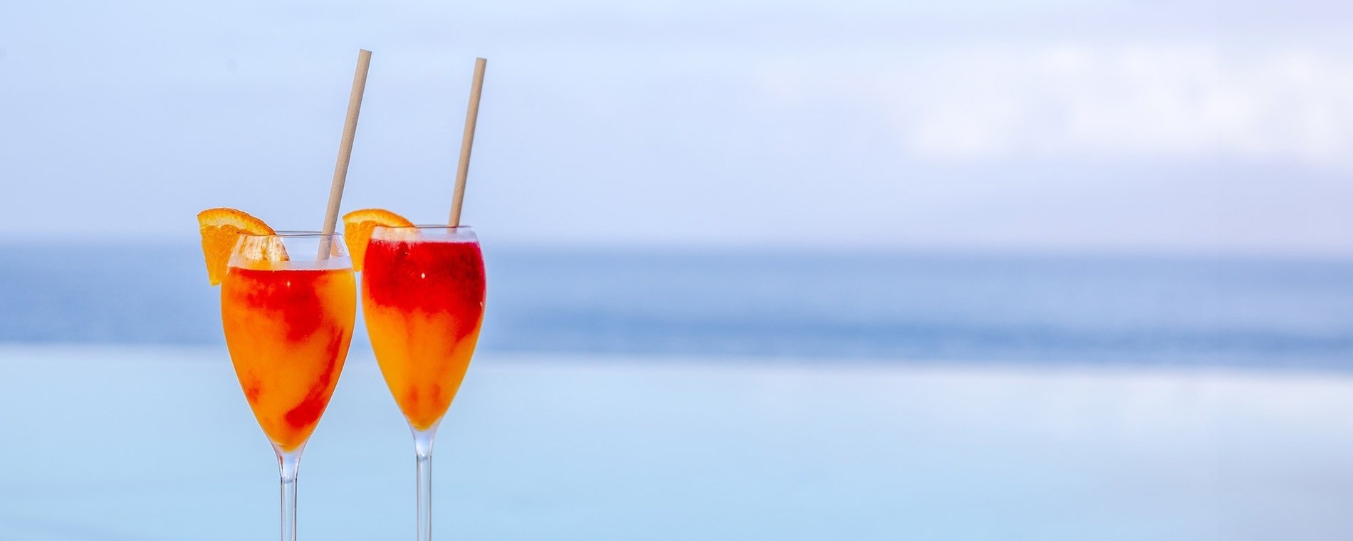 deux verres de boisson orange avec des pailles devant l' océan