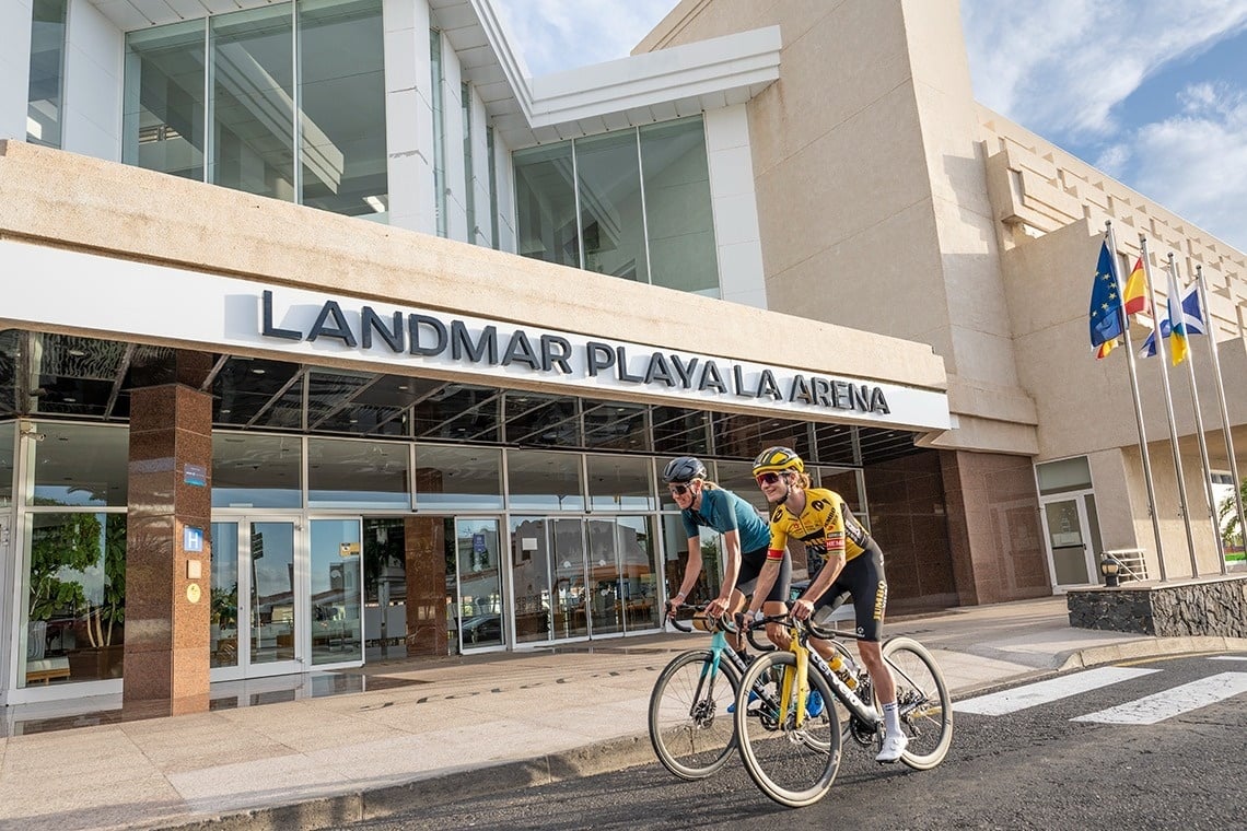 dos personas en bicicleta frente al edificio landmar playa la arena