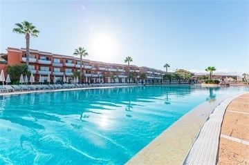 a large swimming pool surrounded by chairs and umbrellas