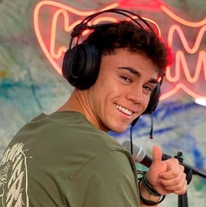 Ein junger Mann trägt Kopfhörer und gibt einen Daumen nach oben .