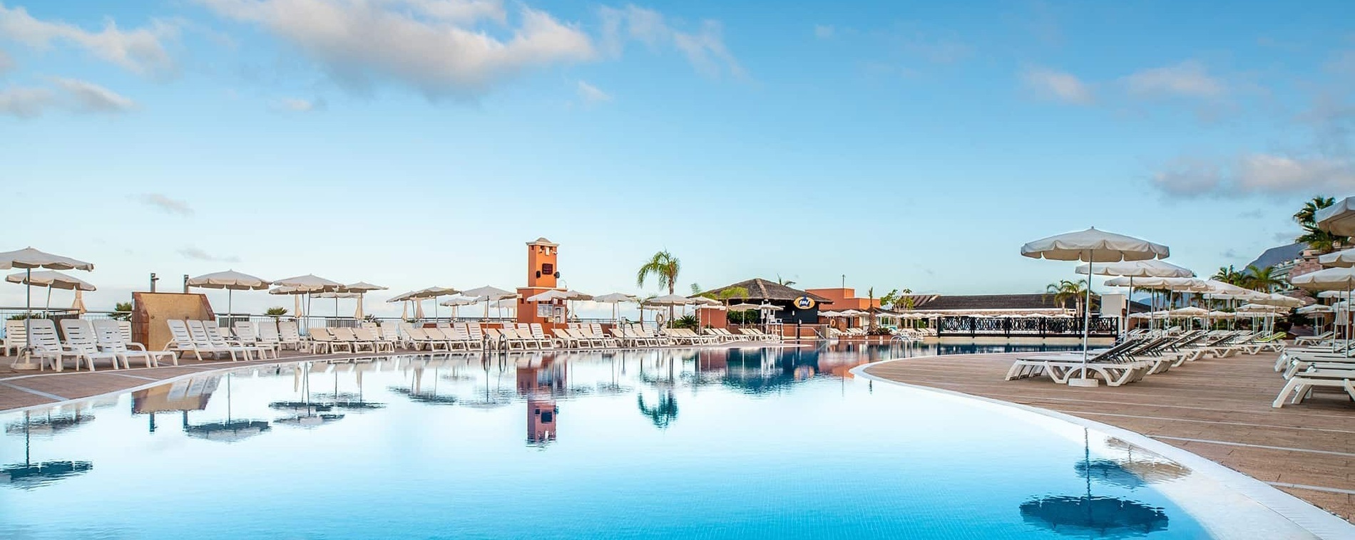 a large swimming pool surrounded by chairs and umbrellas