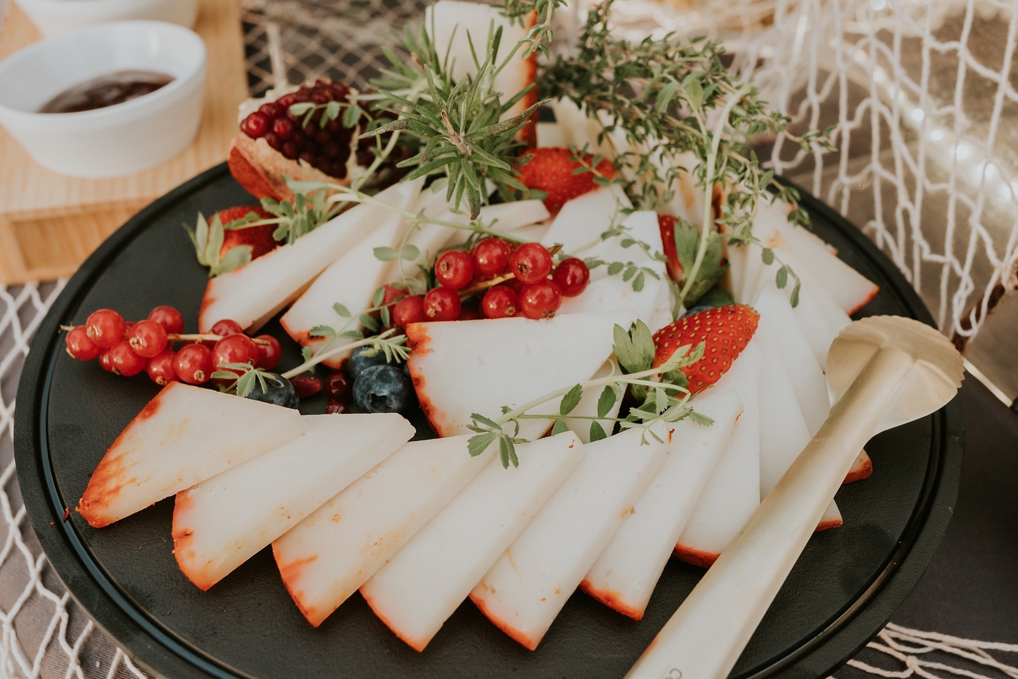 ein Teller mit geschnittenem Käse und Beeren auf einem Tisch