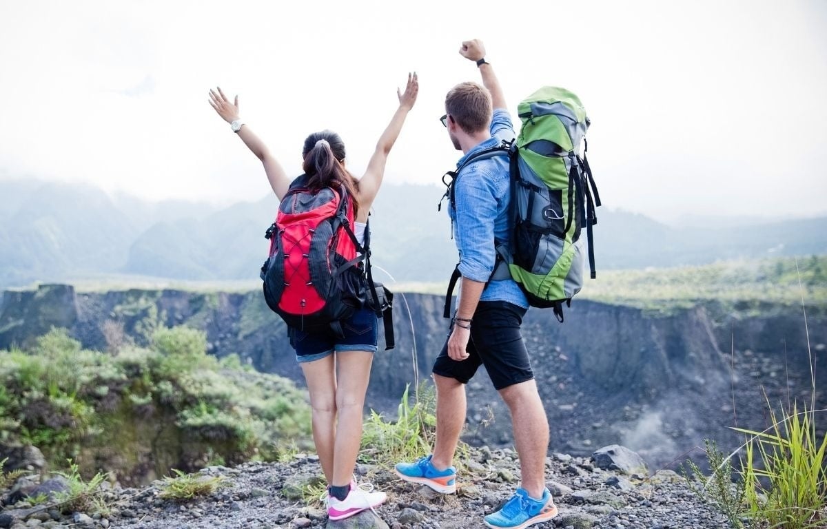 un homme et une femme avec des sacs à dos se tiennent au sommet d' une montagne