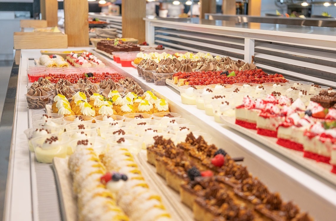 a variety of desserts are displayed on a buffet line