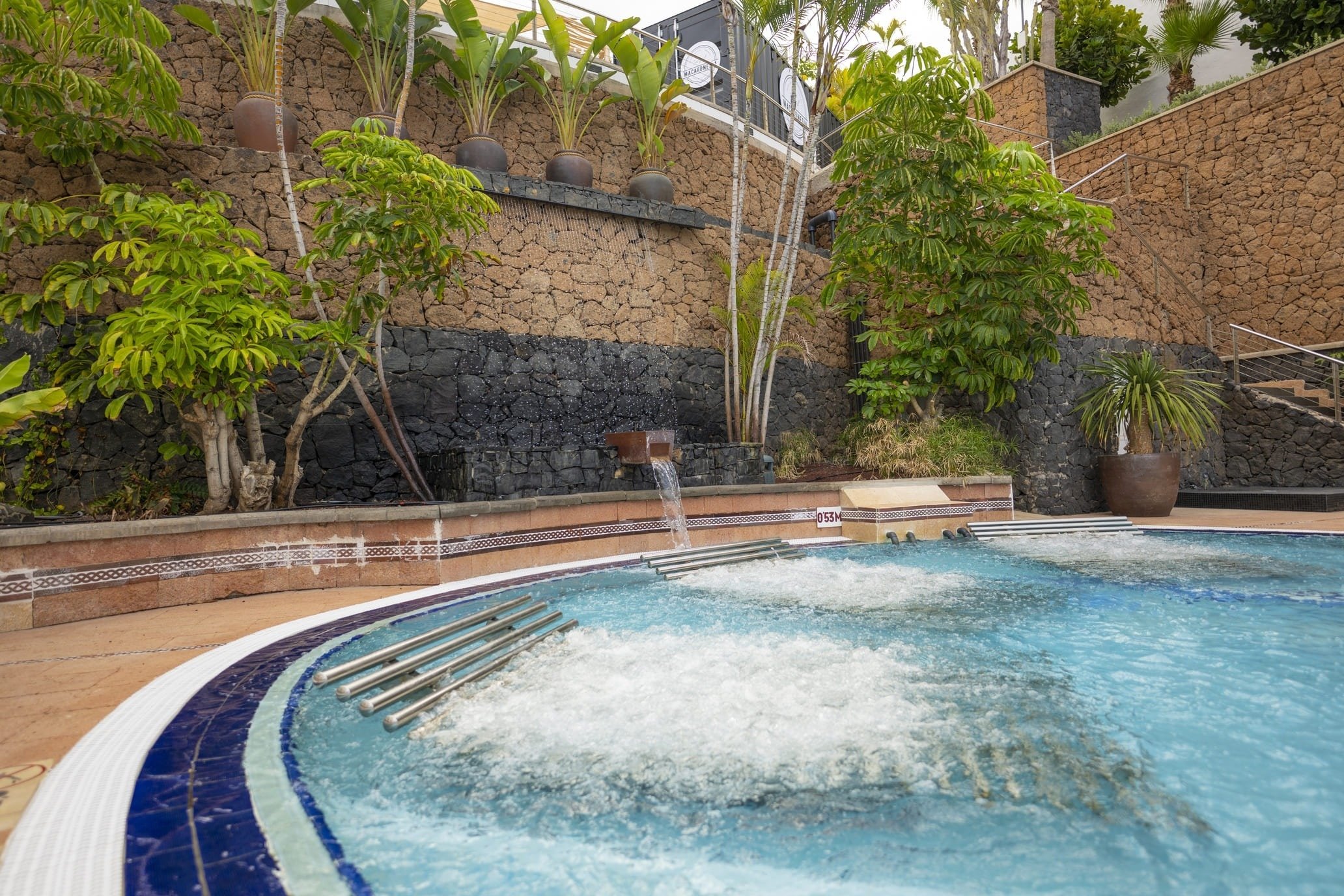 una piscina con un jacuzzi y una cascada en el fondo