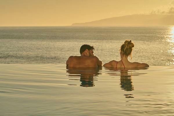 un hombre y una mujer caminan por la playa tomados de la mano