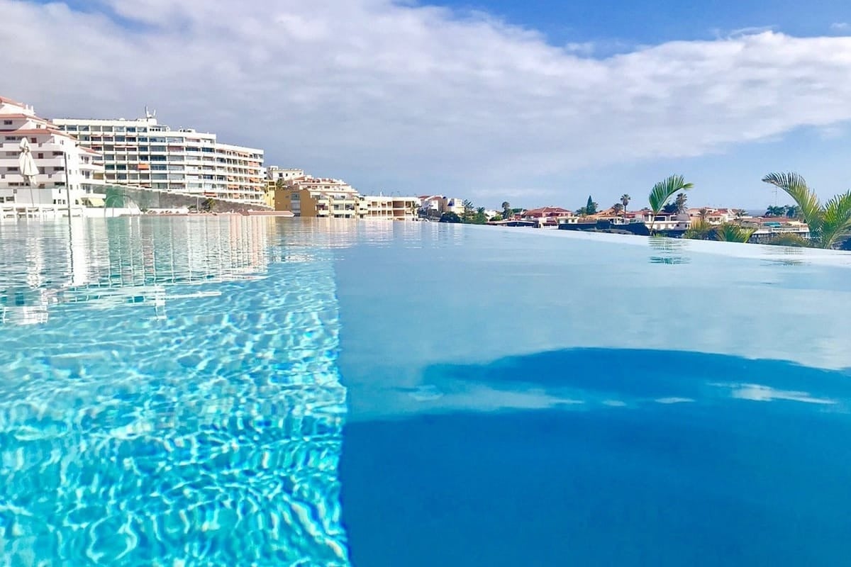 una piscina infinita con edificios en el fondo