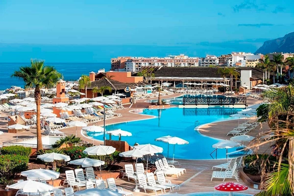 una gran piscina rodeada de sillas y sombrillas en un resort