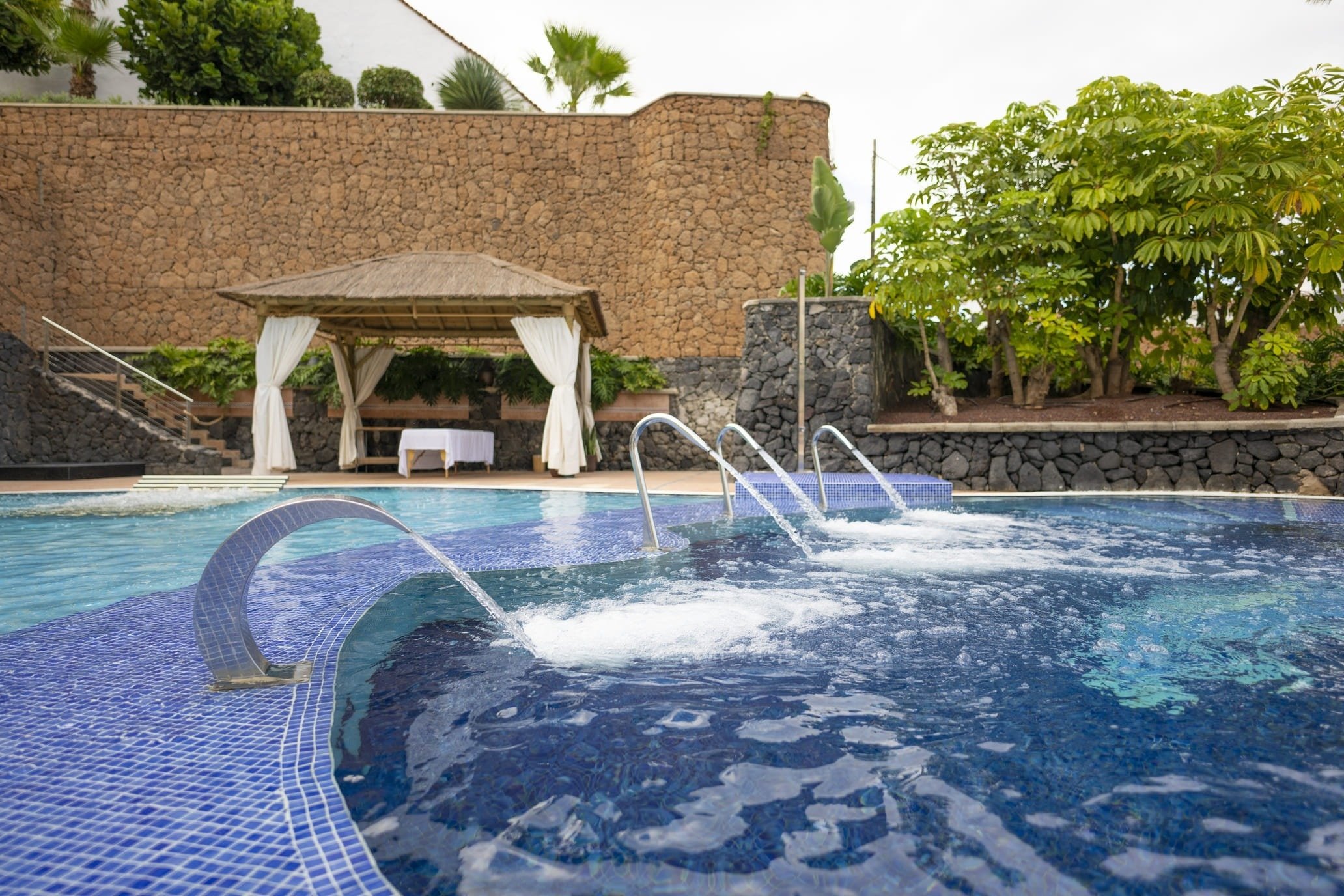 una piscina con jacuzzi y gazebo en el fondo