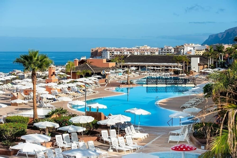 ein großer Pool in einem Hotel mit vielen Sonnenschirmen