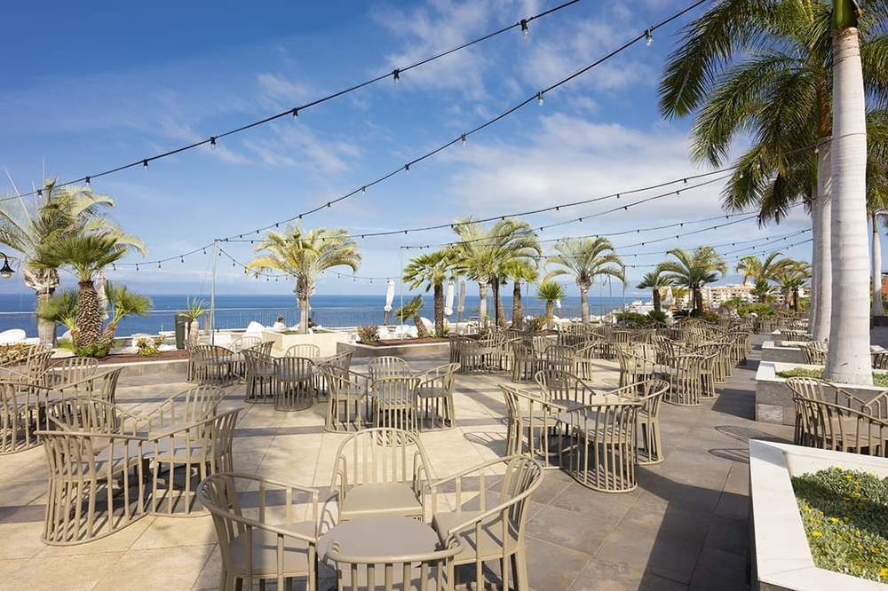 a patio area with tables and chairs surrounded by palm trees