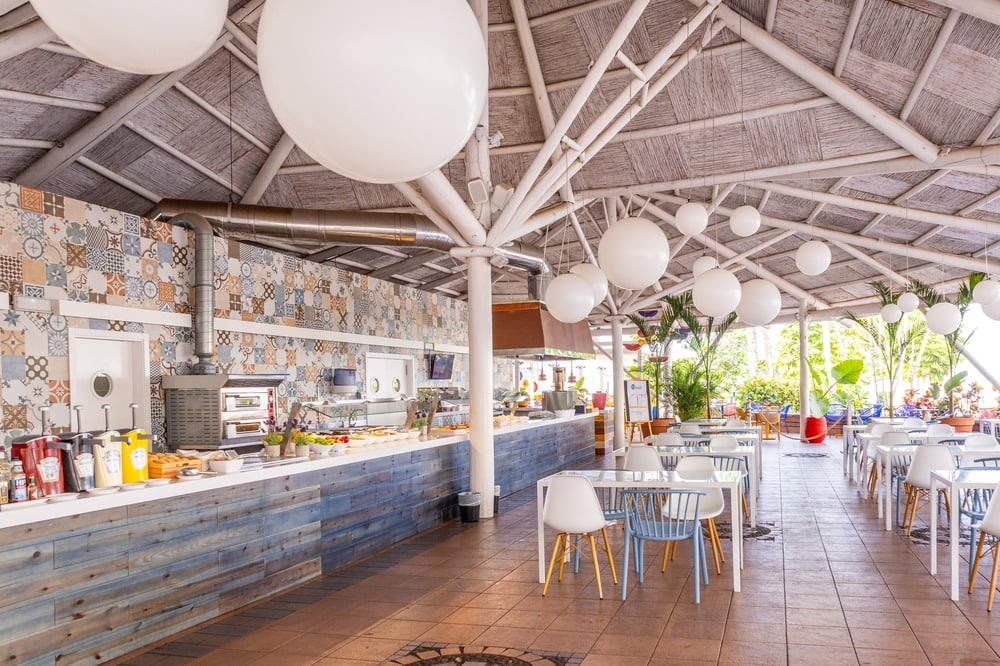 a restaurant with tables and chairs under a white roof