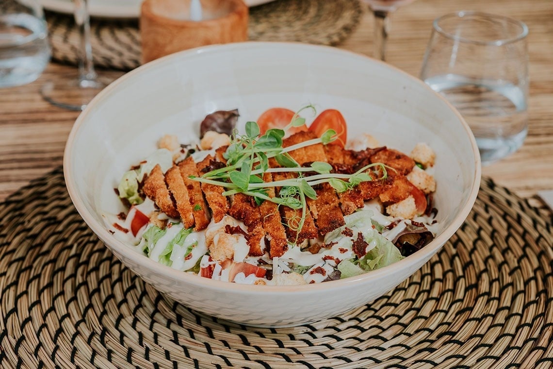 un bol de nourriture est assis sur une table à côté d' un verre d' eau