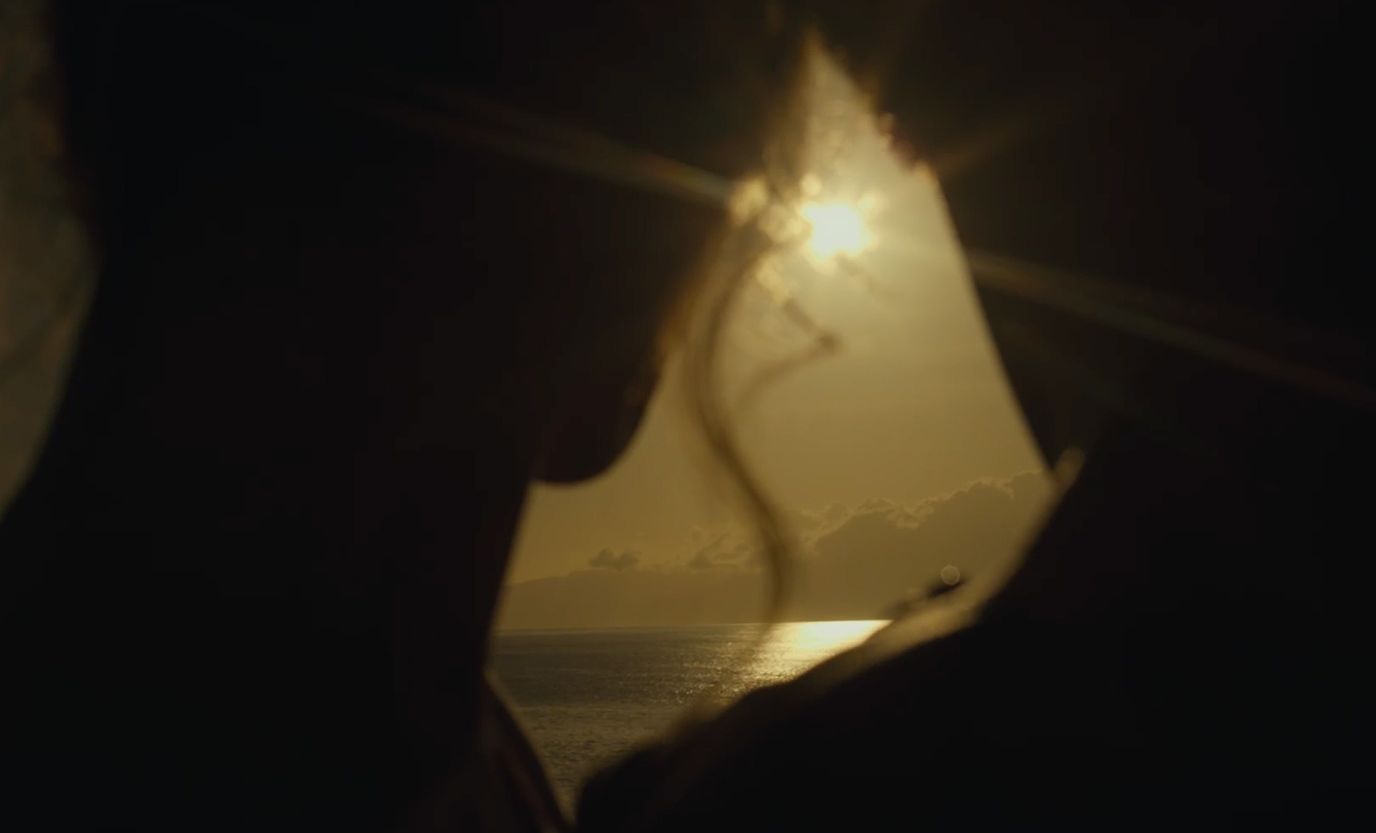 un hombre y una mujer se miran en la oscuridad mientras el sol brilla a través de las nubes