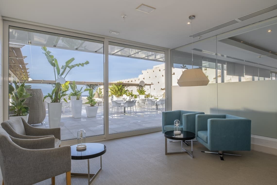 a room with chairs and a table with a view of a balcony