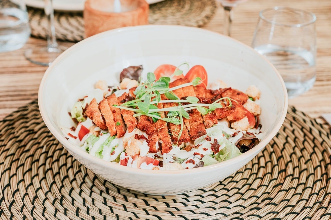 un tazón de ensalada con carne y verduras sobre una mesa