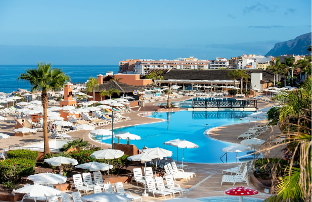 ein großer Pool in einem Hotel mit vielen Sonnenschirmen