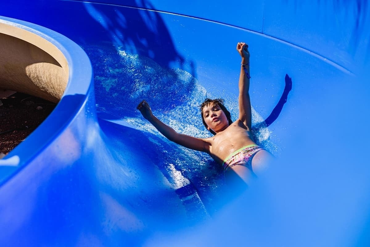 a young girl is sliding down a blue water slide