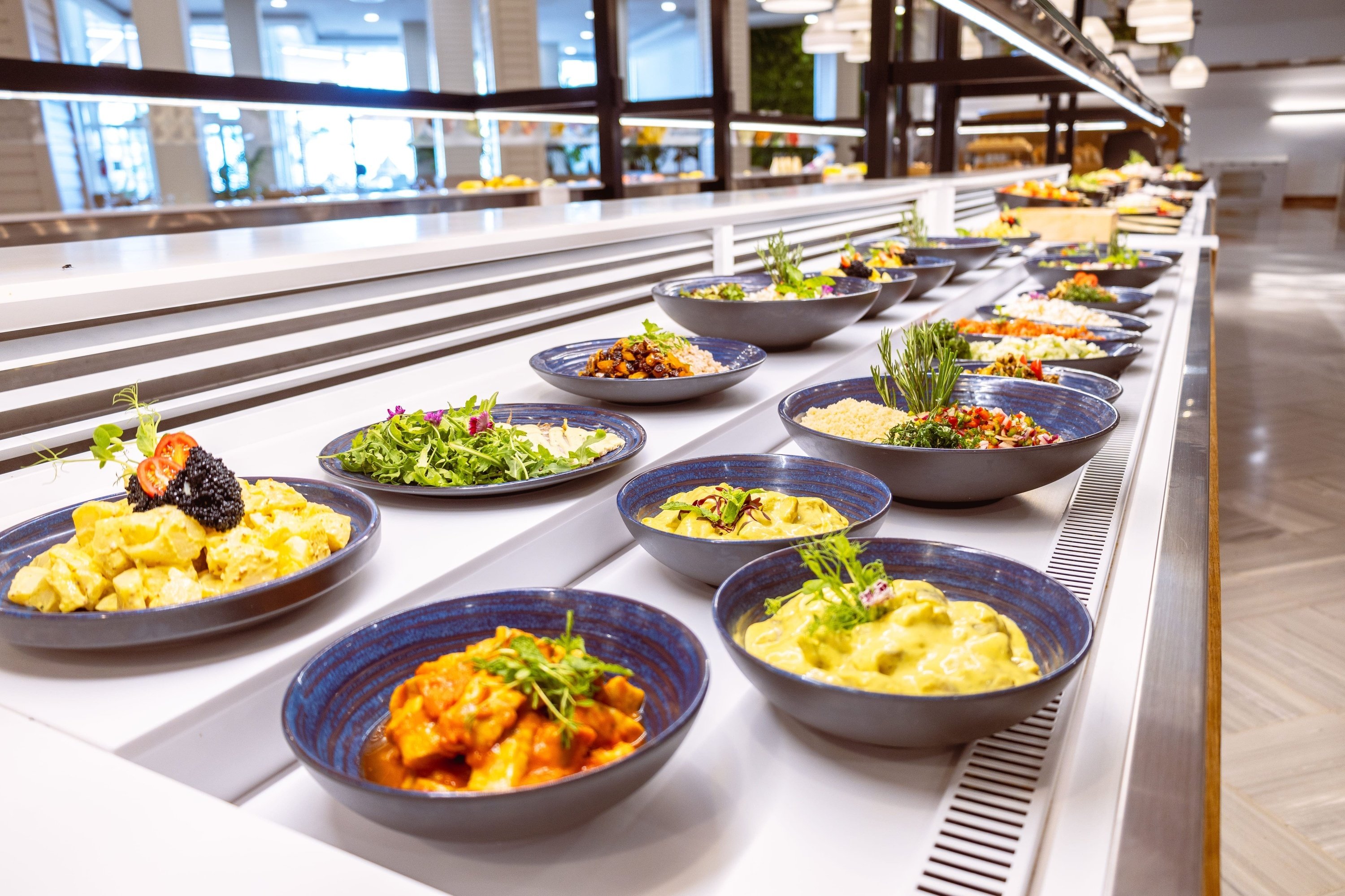 a buffet line with plates and bowls of food