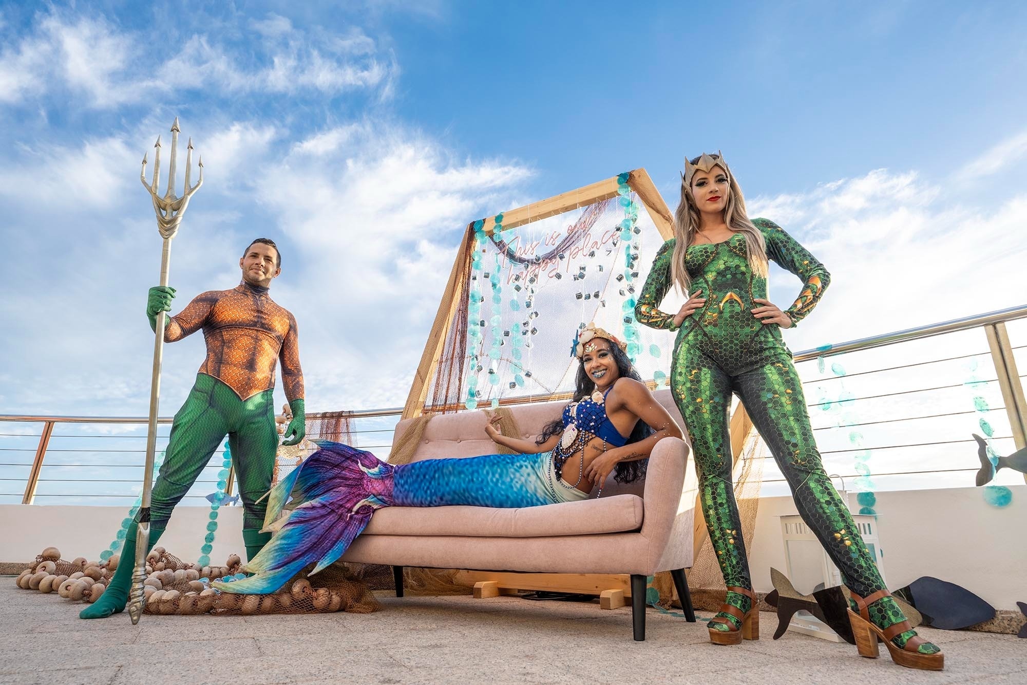 ein Mann in einem Aquaman-Kostüm steht neben zwei Meerjungfrauen