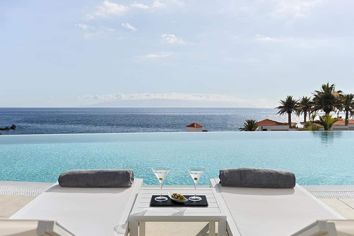 Liegestühle neben einem Infinity-Pool mit Blick auf das Meer