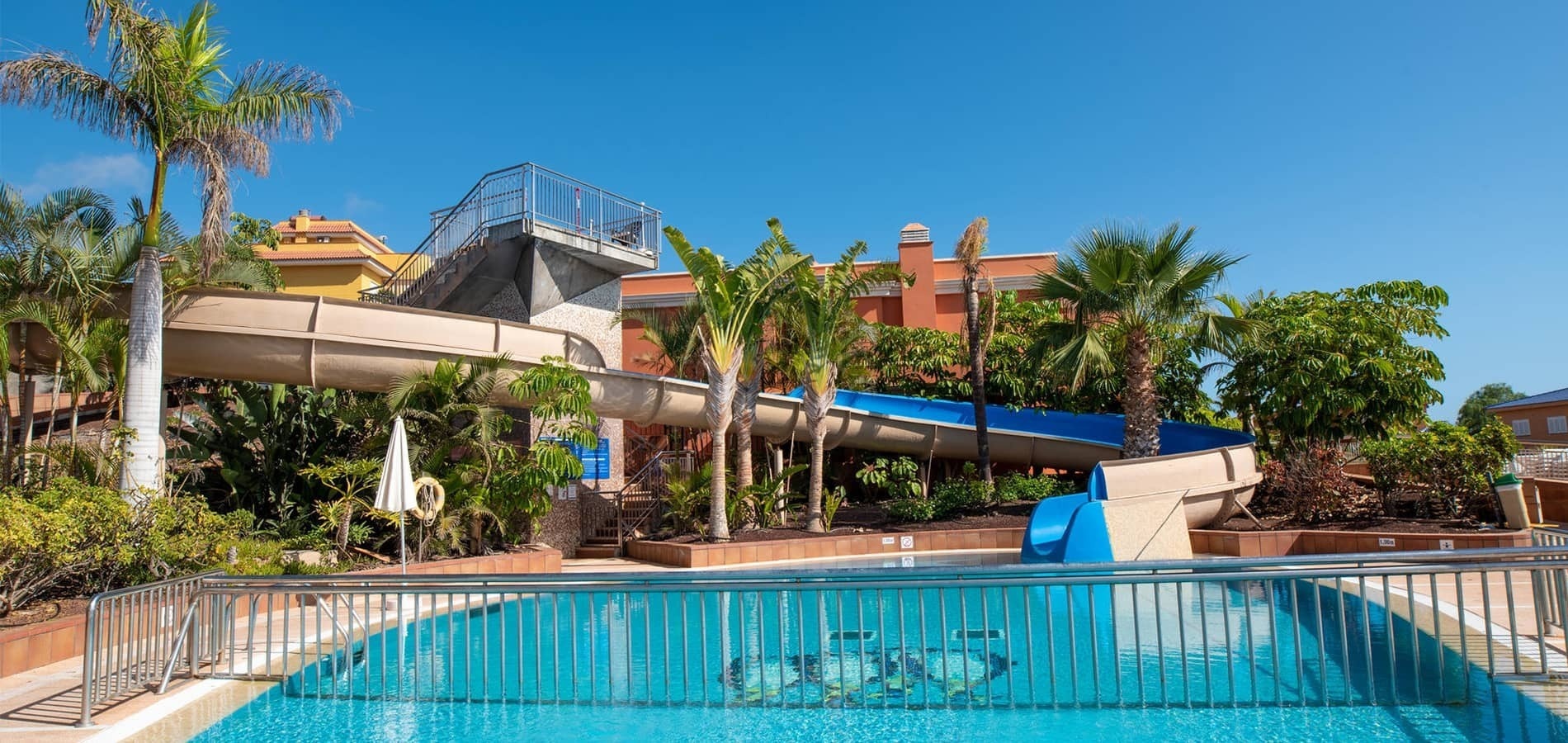 ein Swimmingpool mit Wasserrutsche und Palmen im Hintergrund